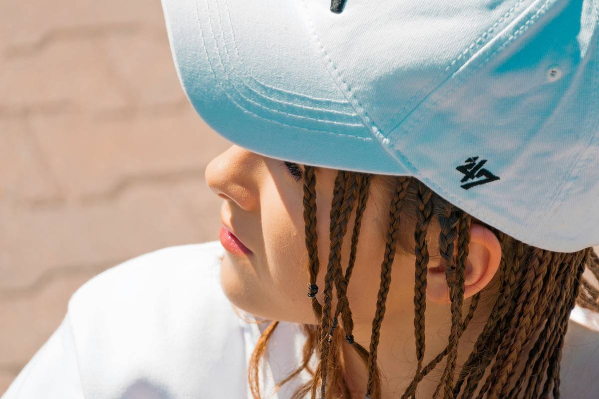 Woman applying hair revitalizing lotion under satin hair cap for deep conditioning