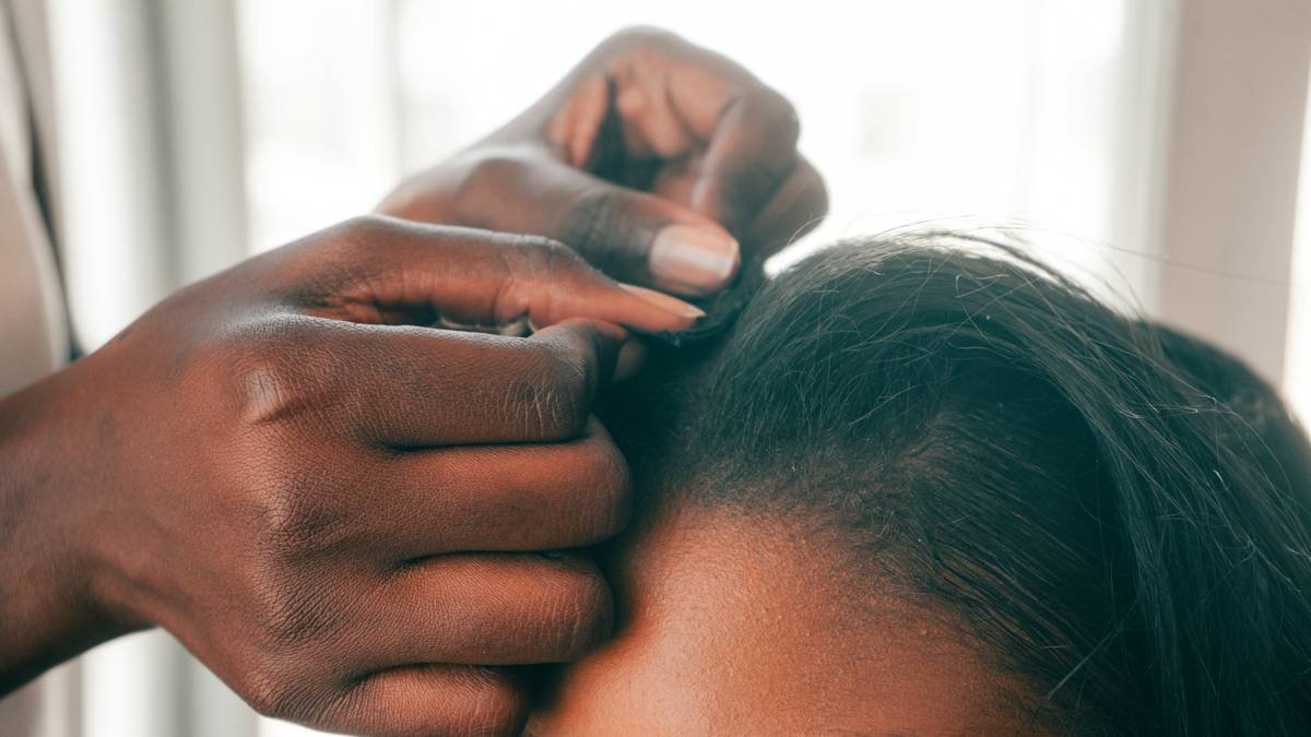 Professional stylist applying salon hair guard to client with braids