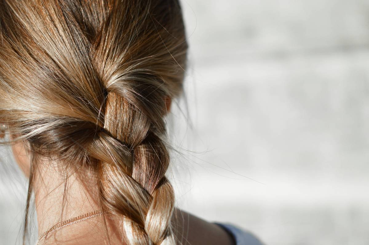 Woman applying hair smoothing balm to damp hair before wearing satin hair cap